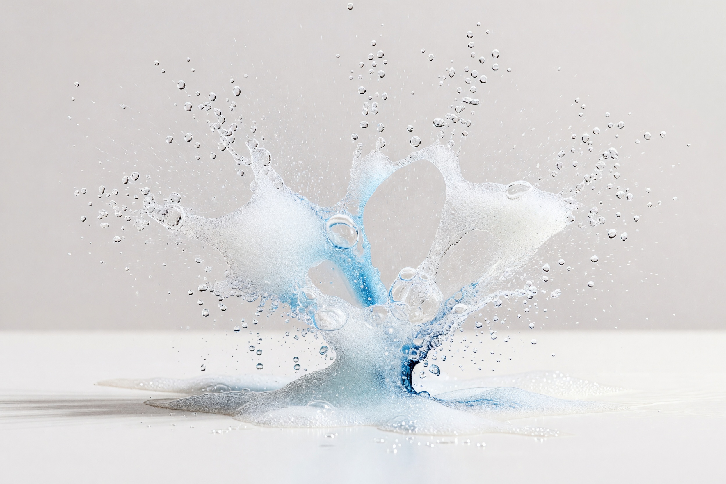 A radiating burst of clean water droplets and light foam, on a clean studio ground