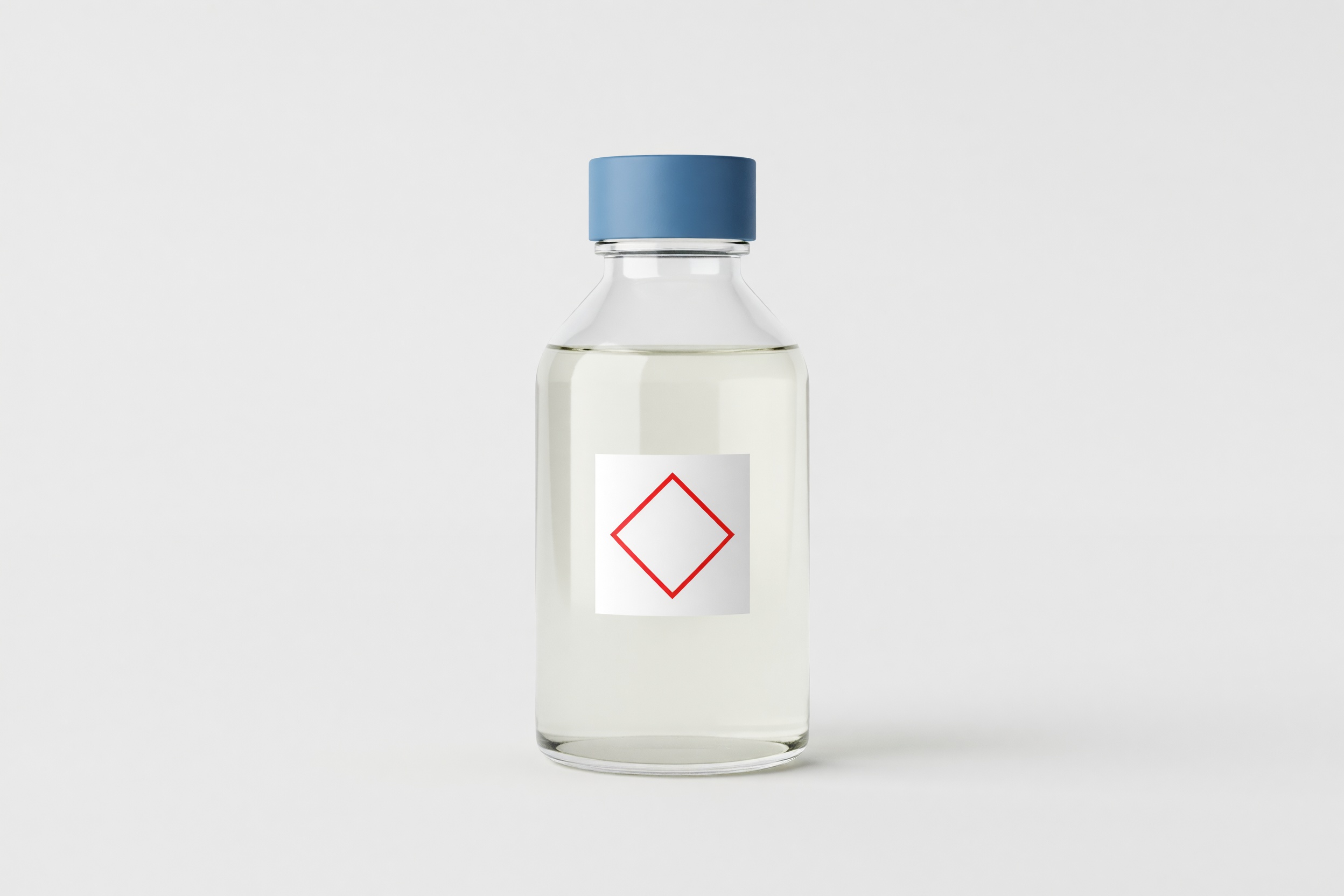 A clear glass laboratory bottle of pale corrosive liquid marked with a red hazard diamond outline, on a clean studio ground.