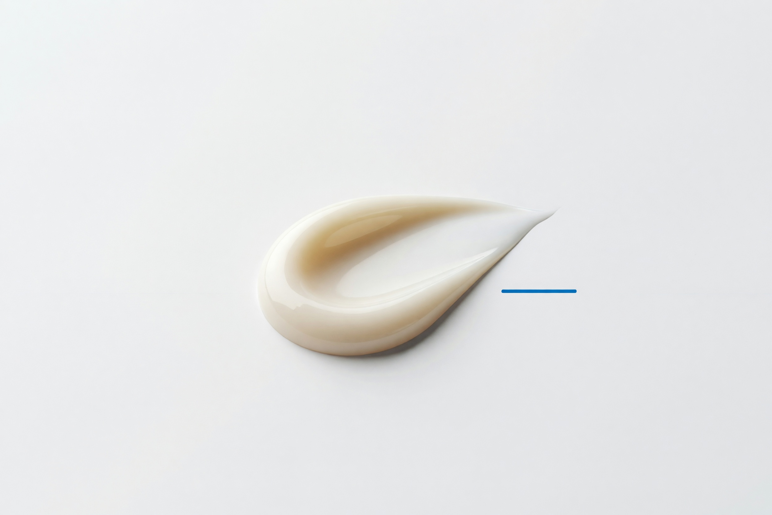 A soft, intact swirl of pale cream emulsion, on a clean studio ground