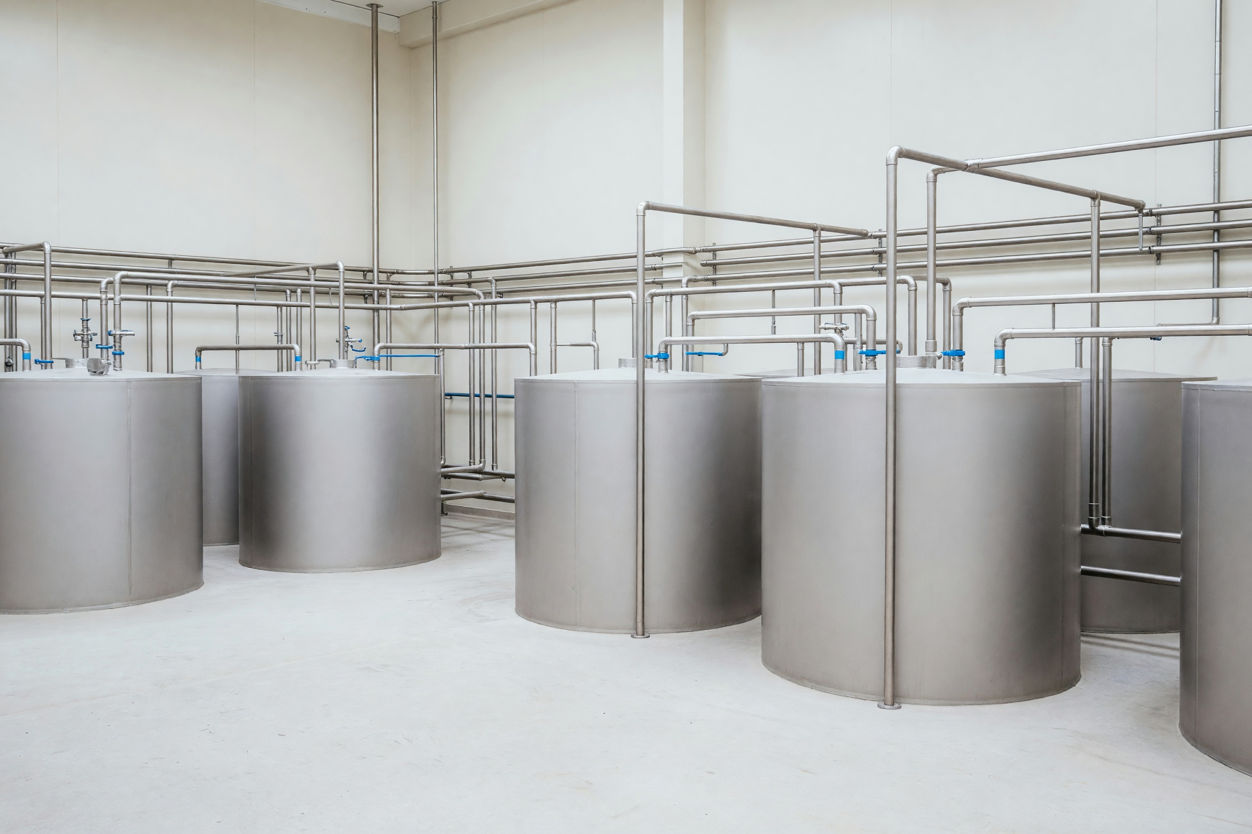 A clean, modern dairy processing plant: rows of polished stainless steel tanks and hygienic pipework