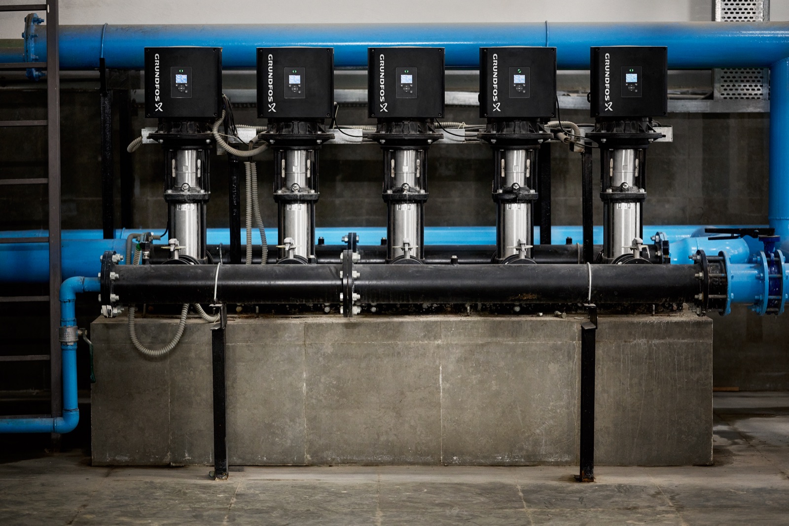 A Grundfos Hydro MPC booster set: five vertical multistage pumps in parallel on a plinth in a plant room